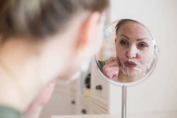 Cosmetic face mask and girl look in the mirror
