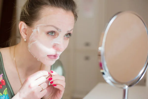 Cosmetic face mask and girl look in the mirror