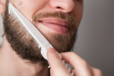 Bir adam tarağıyla sakalını tarıyor