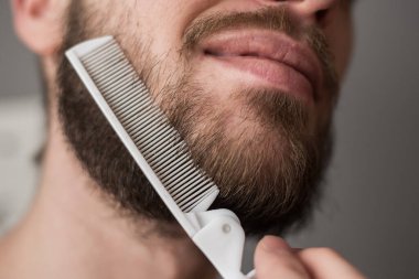 Bir adam tarağıyla sakalını tarıyor