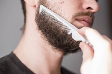 Bir adam tarağıyla sakalını tarıyor