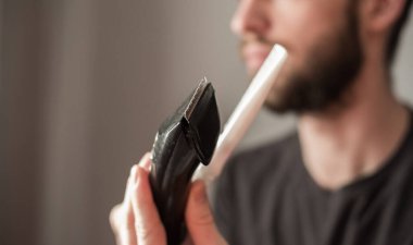 Adam sakalını elektrikli jiletle tıraş ediyor.