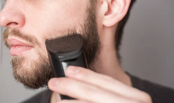 Homem Rapa Sua Barba Com Uma Navalha Elétrica — Fotografia de Stock