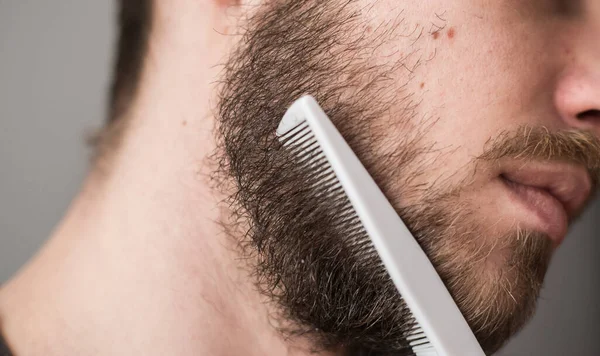 A man combing his beard with a comb