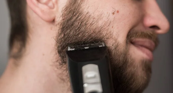 Homem Rapa Sua Barba Com Uma Navalha Elétrica — Fotografia de Stock