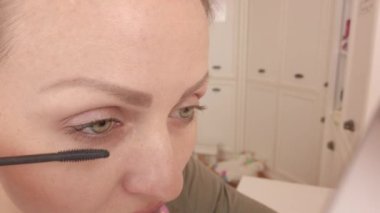 Kız kirpikleri maskarayla boyuyor.