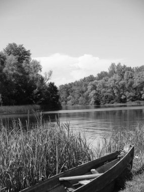 Nehir kıyısına demirlemiş tekne siyah ve beyaz.