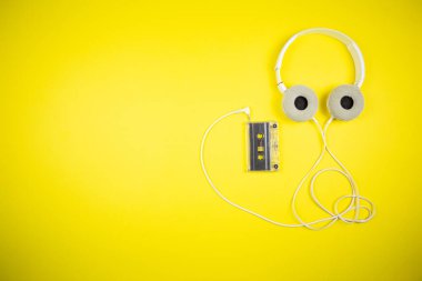 Sarı arka planda ses kaseti ve modern kulaklıklar.
