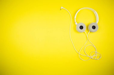 Sarı arka planda 3.5 mm 'lik kabloyla beyaz kulaklıklar.