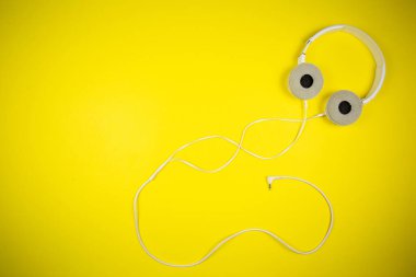 Sarı arka planda 3.5 mm 'lik kabloyla beyaz kulaklıklar.