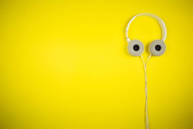 Sarı arka planda 3.5 mm 'lik kabloyla beyaz kulaklıklar.