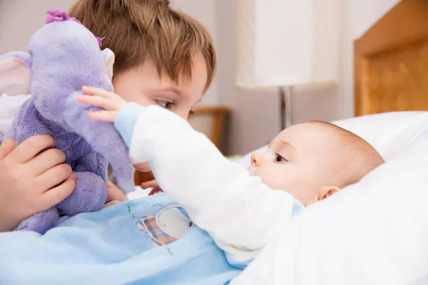 Six year old toddler sharing tender and affectionate moments with his six month old baby sister.