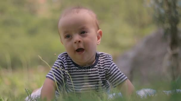 Ein kleines Kind liegt auf dem Gras und weint aus nächster Nähe — Stockvideo