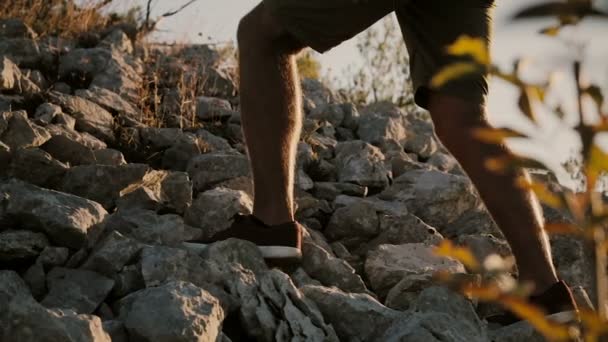 Un homme au coucher du soleil se lève vers une montagne avec un sac à dos . — Video