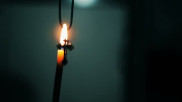 Крест на фоне горящей свечи в церкви — стоковое видео