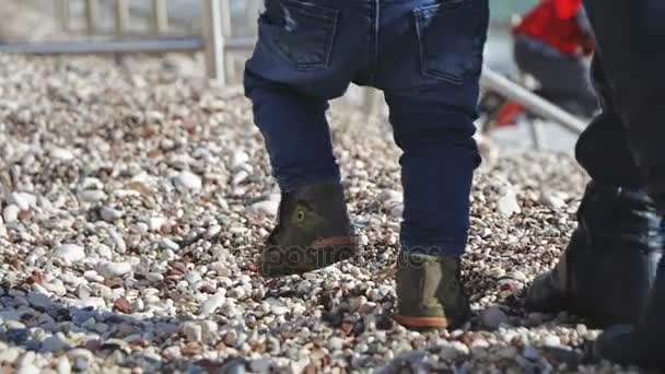 Menino de 1 ano de idade andando seus primeiros passos, boneca disparada em pabbles — Vídeo de Stock