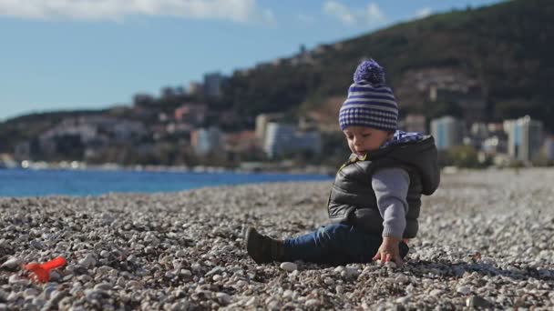 Un niño en la playa se arrastra sobre guijarros . — Vídeos de Stock