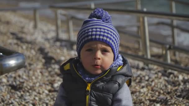 Un niño con sombrero de invierno sonríe a la cámara — Vídeos de Stock