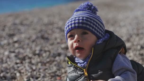 Ett barn på stranden kryper på grus. — Stockvideo