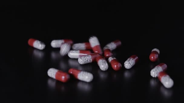 Pílulas médicas espalhadas na mesa preta — Vídeo de Stock