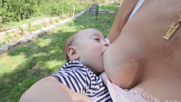 Una madre alimenta su leche materna y arrulla a su bebé — Vídeo de stock