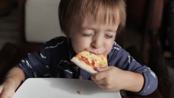 Κοντινό πλάνο του μικρού χαριτωμένου αγοριού που τρώει πίτσα. Ουδέτερα χρώματα για διόρθωση κολάρου. — Αρχείο Βίντεο