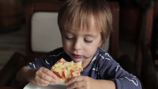 Крупним планом маленький симпатичний хлопчик їсть піцу. Нейтральні кольори для корекції кольору . — стокове відео