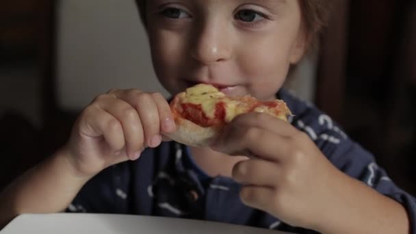 Κοντινό πλάνο του μικρού χαριτωμένου αγοριού που τρώει πίτσα. Ουδέτερα χρώματα για διόρθωση κολάρου. — Αρχείο Βίντεο