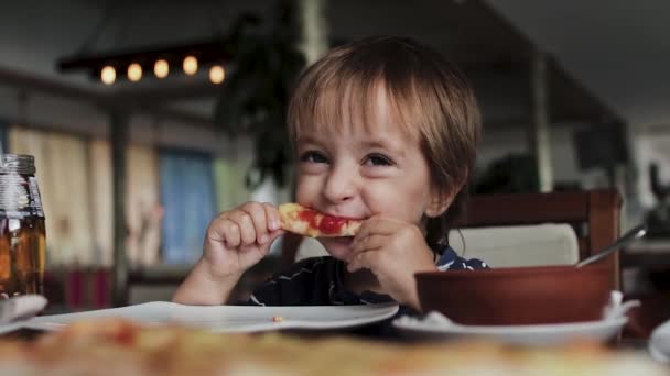 Gros plan du petit garçon mignon qui mange de la pizza. Couleurs neutres pour la correction du collet . — Video