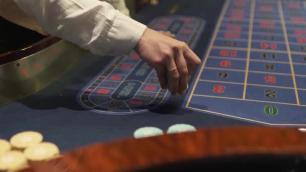 Distribuidor trabaja en el casino de mover fichas con sus manos en la mesa de juego — Vídeo de stock