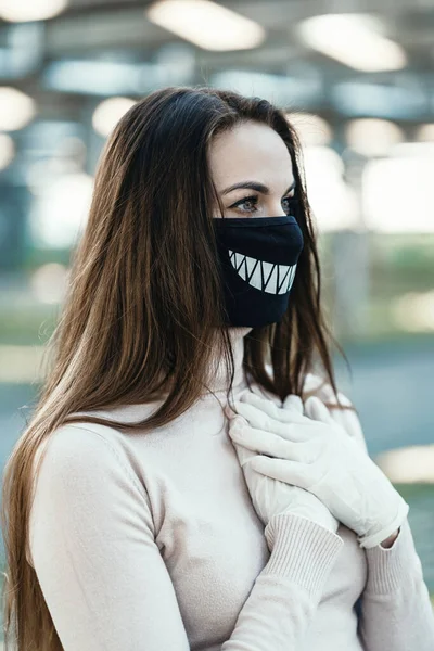 Giovane ragazza in maschera medica divertente e guanti Foto Stock