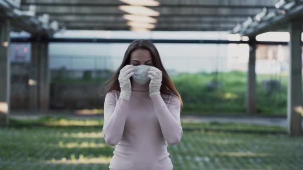 Egy lány orvosi maszkban és kesztyűben megy a kamerába. — Stock videók