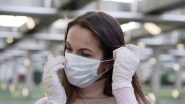 Koruyucu eldivenli bir kadın yüzüne koruyucu maske takıyor.