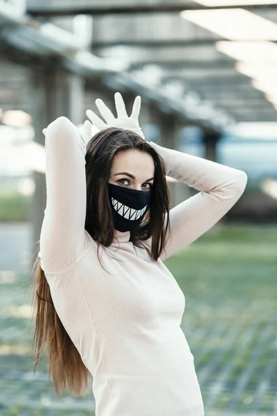 Yüzünde çizilmiş dişleri olan komik koruyucu maskeli bir kız.