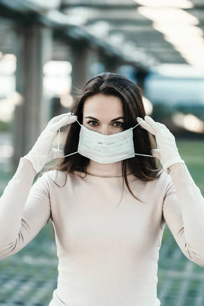 Una chica con hermosos ojos lleva una máscara protectora en la cara con guantes de goma Imagen De Stock