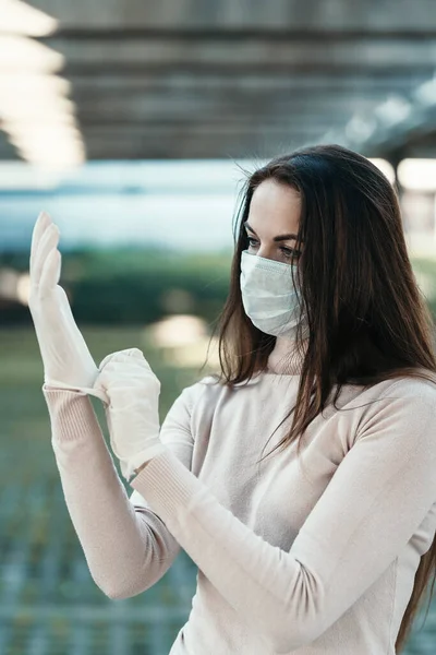 Una chica con hermosos ojos lleva una máscara protectora en la cara con guantes de goma Imagen De Stock