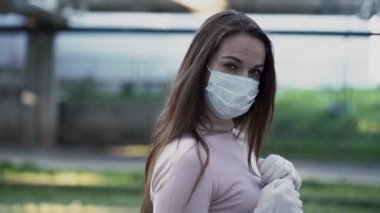 Tıbbi maskeli ve eldivenli genç kız dur işareti gösteriyor.