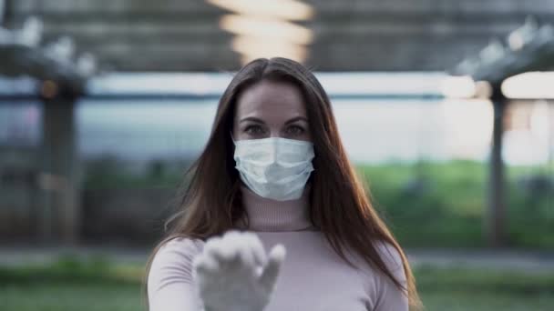 Νεαρή κοπέλα με ιατρική μάσκα και γάντια δείχνει στοπ. — Αρχείο Βίντεο