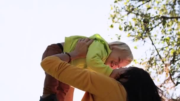 Mladá matka hází dítě s rukama paprsky slunce zářit ve fotoaparátu — Stock video