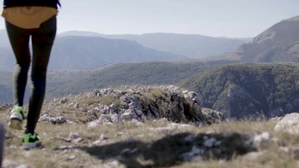 Uma jovem em roupas esportivas caminha no topo da montanha — Vídeo de Stock