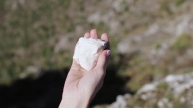 Kadın eli beyaz taşı tutar.