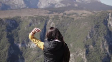 Kız uçurumun kenarında duruyor ve bir taş atıyor.