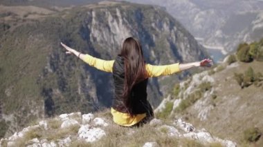 Dağ rüzgarının tepesinde oturan kız uzun saçlarını uzatır.