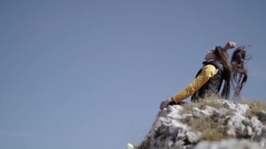 Kız dağın tepesinde oturur ellerini açar ve rüzgar eser.