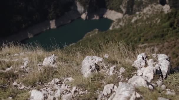 Stenen en gras op de top van de berg onder de canyon en het bergmeer — Stockvideo