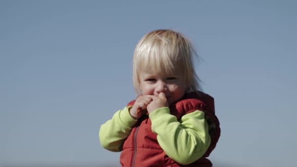 Little boy with blond hair looks shyatatto at the camera — Stock Video