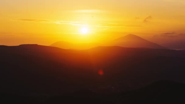De zon gaat onder tegen de achtergrond van bergen en wolken van de zonsondergang — Stockvideo