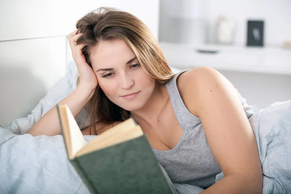 Mädchen liest Buch zu Hause im Bett — Stockfoto