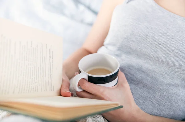 Девушка читает книги и пьет кофе в постели дома — стоковое фото