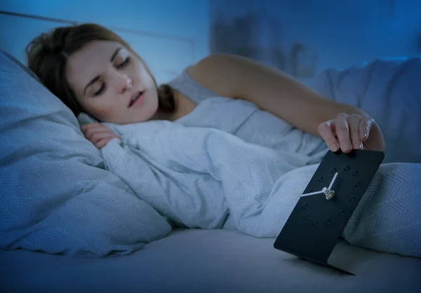 Девушка в постели ночью проверяет часы, бессонница концепция проблемы сна — стоковое фото
